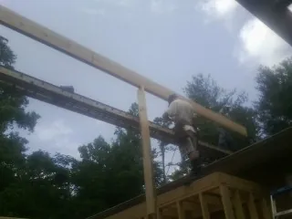 Carpenter setting a ridge beam over a new addition frame — Ice Dam Removal by Roofing Brothers in College Point