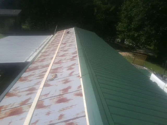 Old rusted panels beside newly installed green metal roofing — Wind Damage Roof Repair by Roofing Brothers in College Point