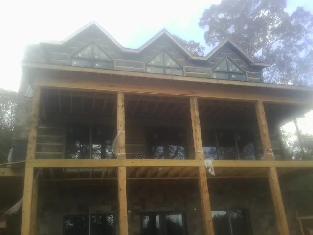 Dormers and porch framing on a large log home under construction — Roof Coating work by our crew in College Point