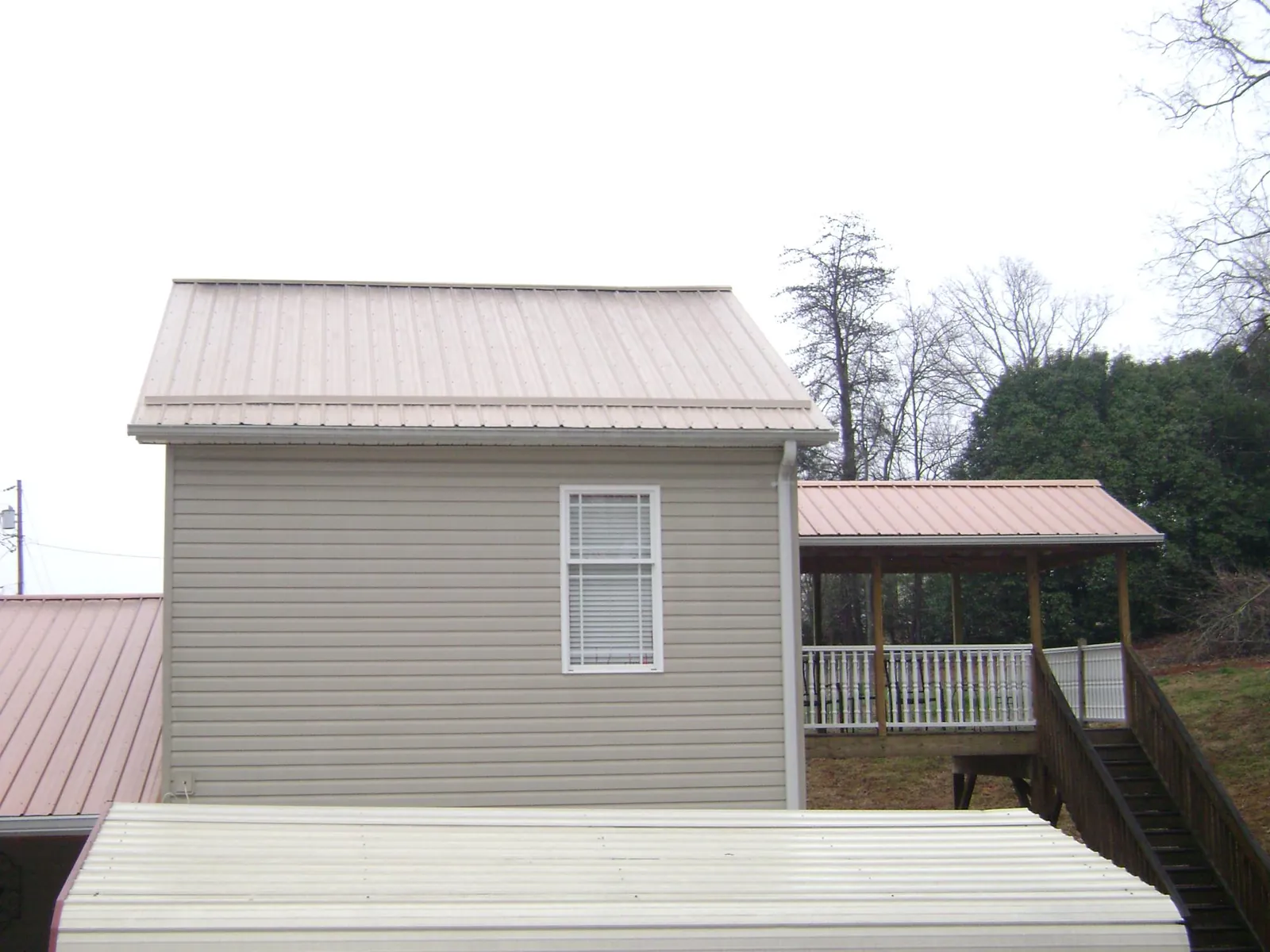 Tan metal roofs on a two story addition and attached porch, from a Roof Replacement job in College Point