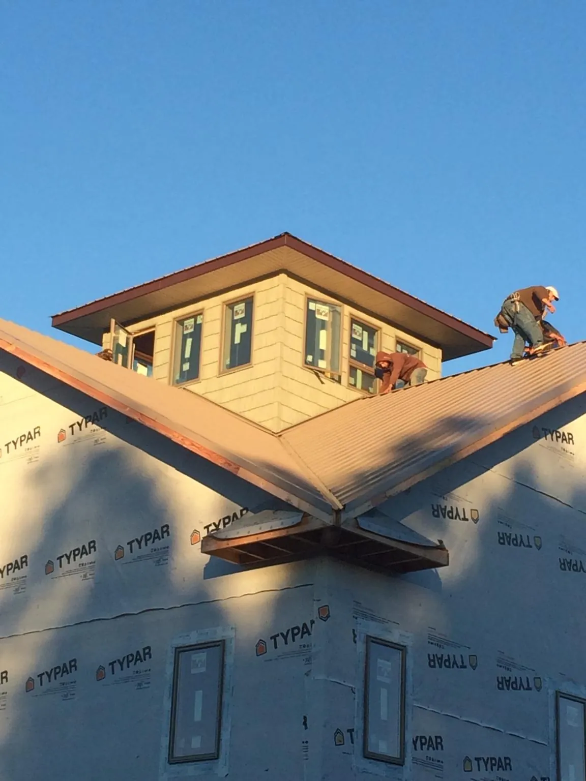 Roofers working around a rooftop cupola on a new metal roof at sunset — Roof Waterproofing in College Point by Roofing Brothers